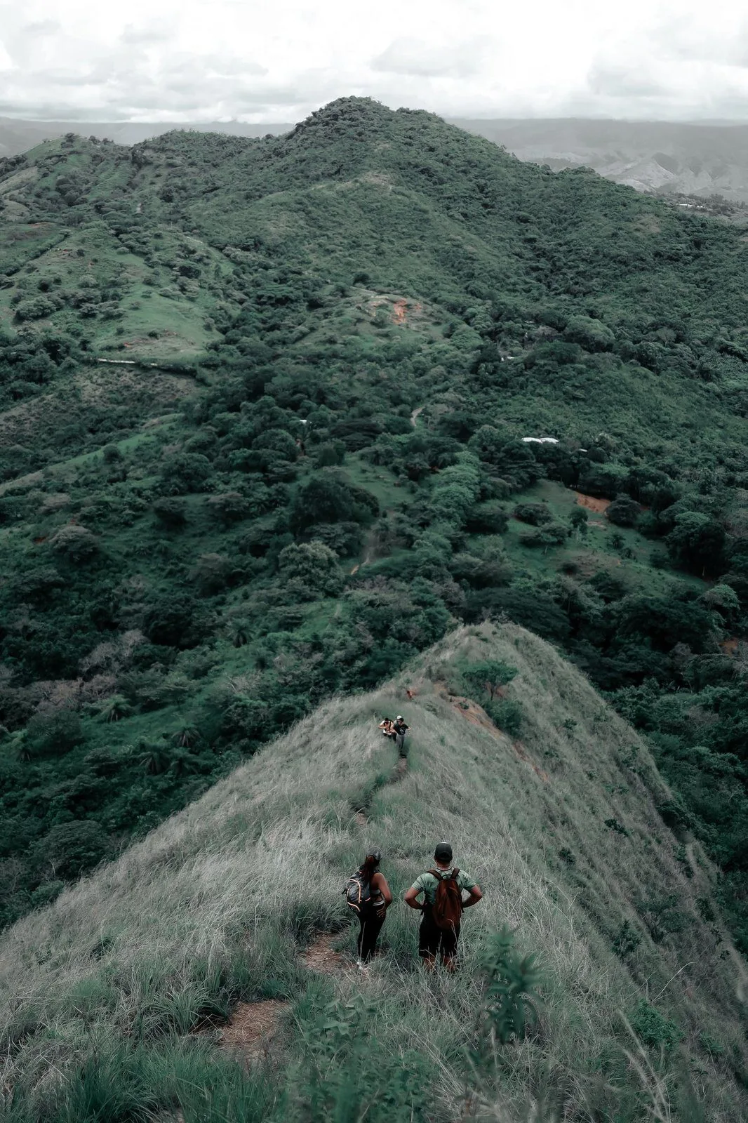 Two hikers pausing on a green mountain ridge