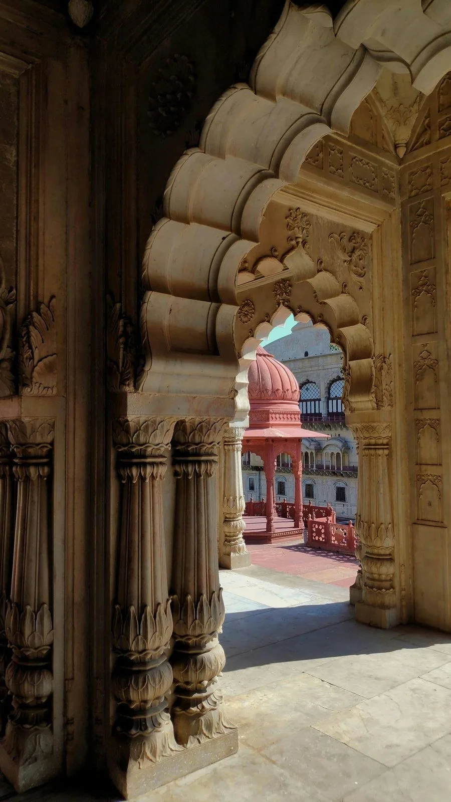 A red domed pavilion framed by a carved marble archway